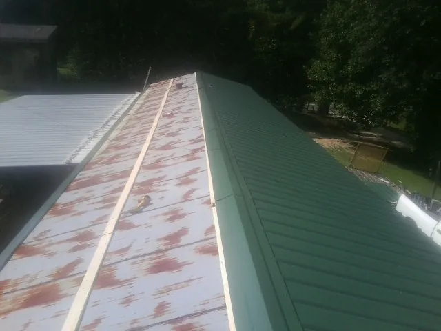 Old rusted panels beside newly installed green metal roofing — Wind Damage Roof Repair by Roofing Brothers in Clarkesville