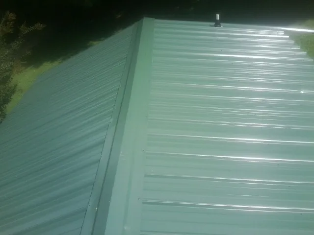New green metal panels meeting at the ridge of a roof — Flat Roof Repair work by our crew in Clarkesville