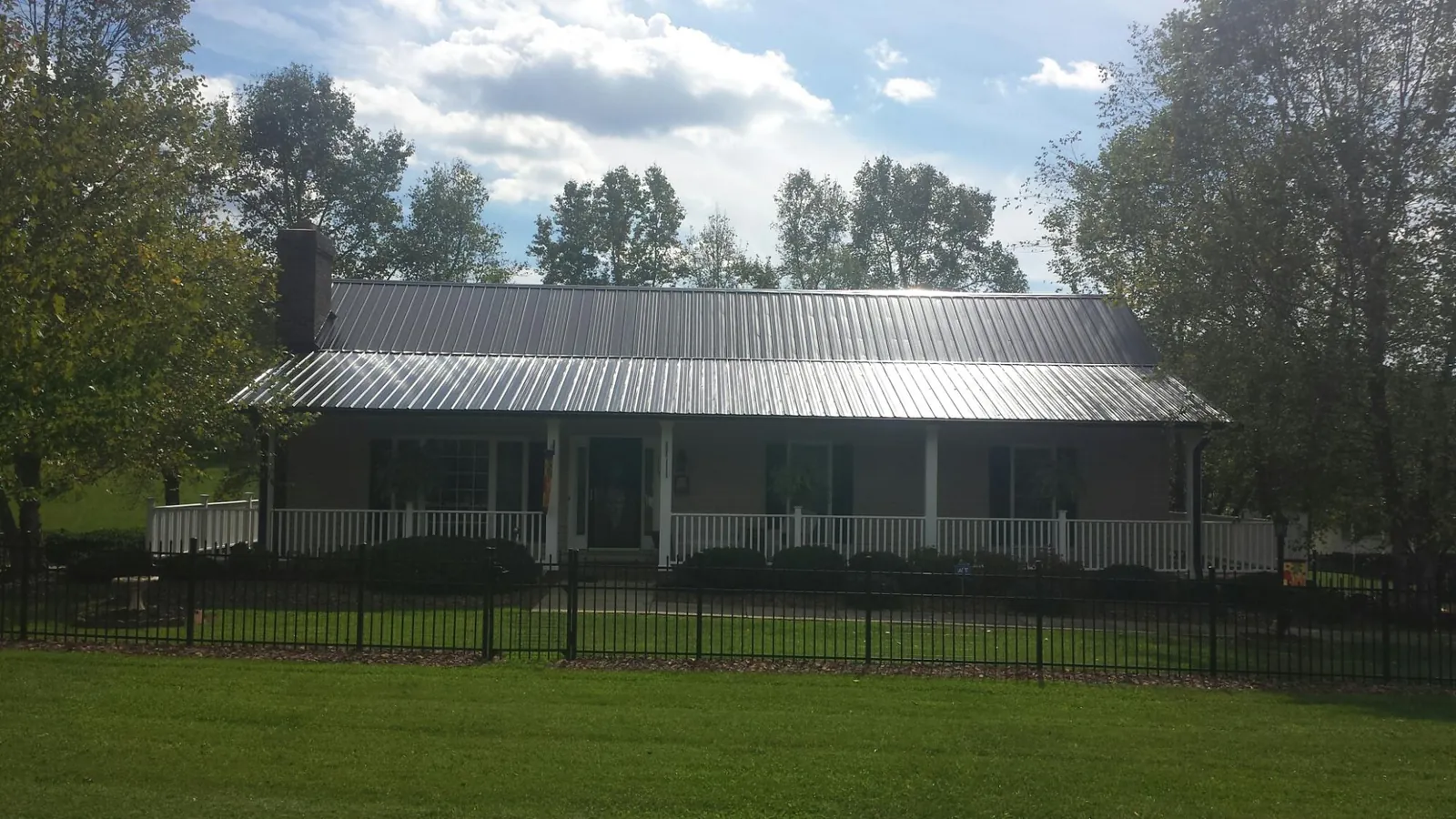 Gray metal roof on a brick ranch with a full width front porch — Gutter Guard Installation work by our crew in Clarkesville